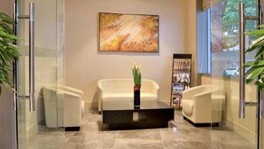A modern lobby with a glass partition, two white sofas, a black coffee table, and a large abstract painting on the wall. - Shundi SHY Hotel West Lake Hangzhou (Hangzhou)