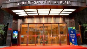 The exterior of Shun Di San He Yuan Hotel with a modern facade, large glass entrance, and a red carpet leading to the doors. - Shundi SHY Hotel West Lake Hangzhou (Hangzhou)