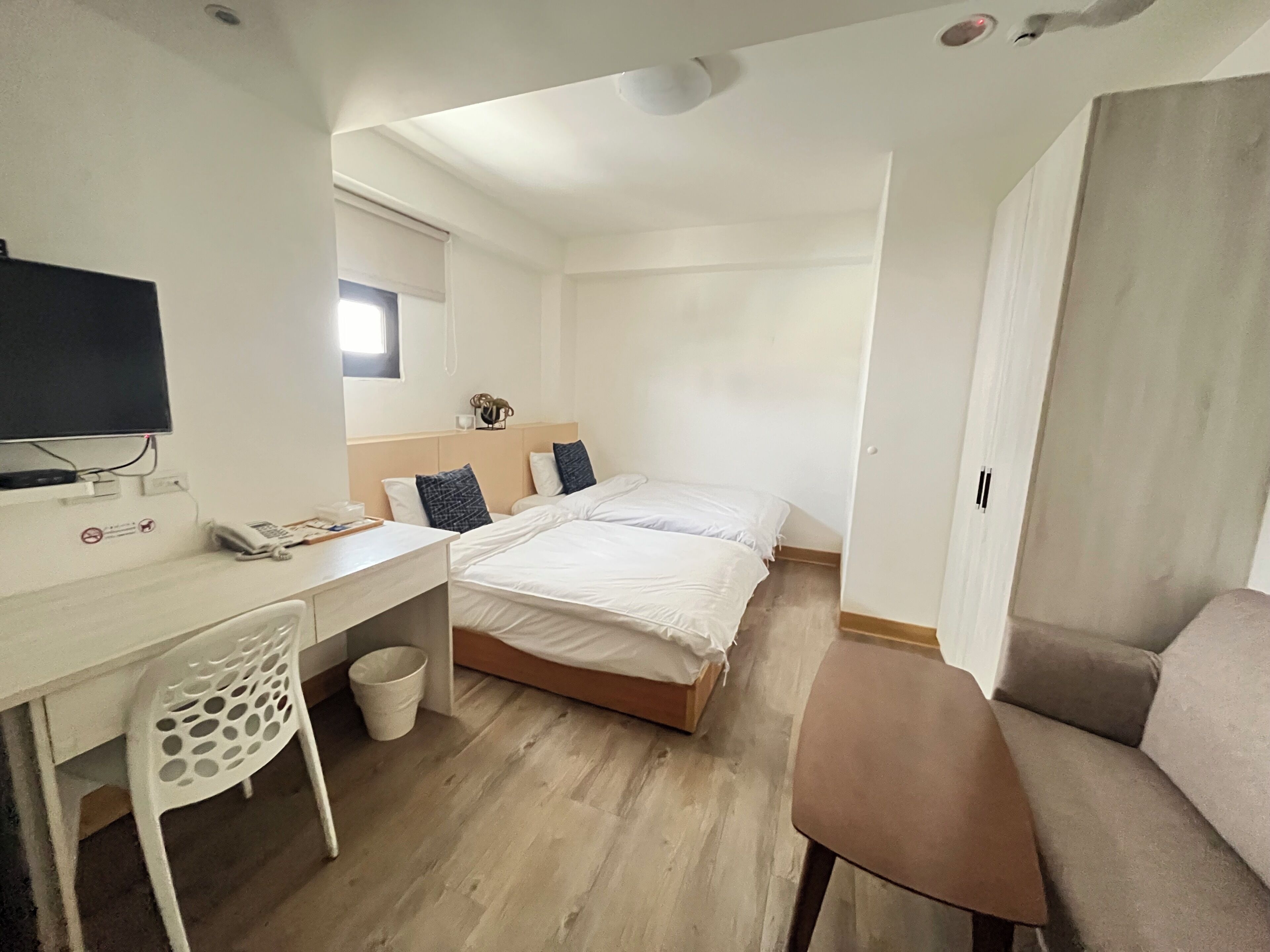 A compact hotel room with a bed, a desk, a chair, and a television.
