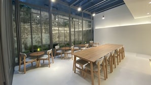 A modern meeting room with a large wooden table and chairs, large windows, and a skylight. - Huru House (Taichung)