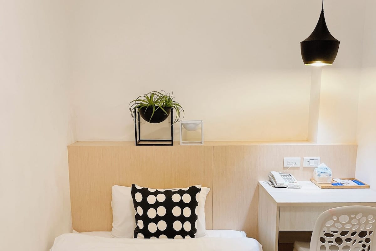 A small, neatly arranged bedroom with a bed, a desk, and a chair.