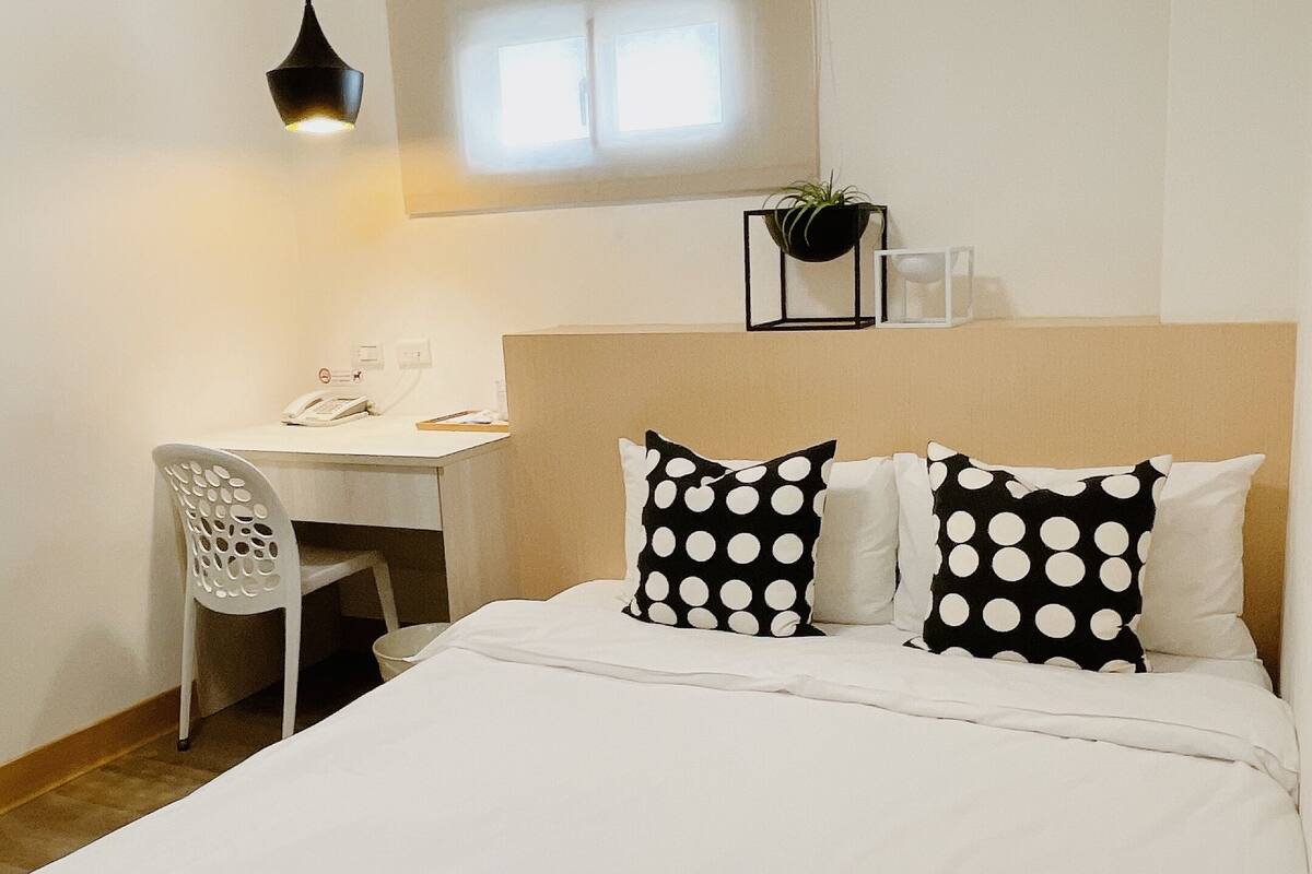 A bedroom with a bed, a desk, and a chair.