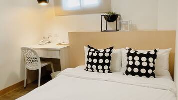 A bedroom with a bed, a desk, and a chair.