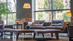 A modern interior with a leather sofa, a coffee table, and two floor lamps. Large windows provide a view of the outside. - Shundi SHY Hotel Jinshan Lake Zhenjiang (Zhenjiang)