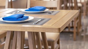 A dining area with wooden tables and chairs, each set with a plate, folded napkin, and cutlery. - Shundi SHY Hotel Jinshan Lake Zhenjiang (Zhenjiang)