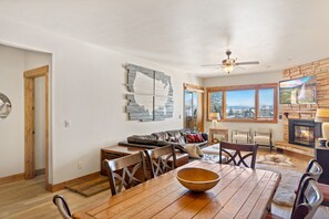 Cozy living area with a dining table for four, fireplace, and large window offering a view of the outdoors.