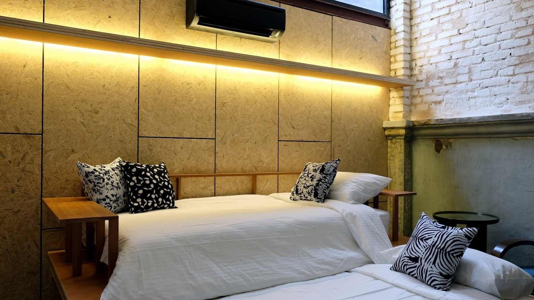 Quarto de hotel com uma cama grande, duas mesas de cabeceira e uma mesinha redonda.