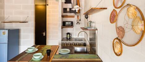 Una cocina con encimera de madera rústica, un fregadero y una estufa. Hay conchas decorativas en la pared y un pequeño estante con utensilios de cocina.