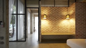 A modern hotel room with exposed brick walls, a large window with sheer curtains, and a hanging light fixture. - Belakang Kong Heng by DreamScape (Ipoh)