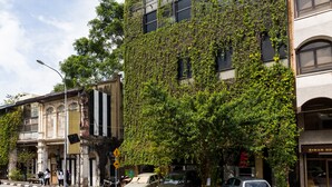 A building with a modern facade, a tree-lined street, and parked cars. - Belakang Kong Heng by DreamScape (Ipoh)