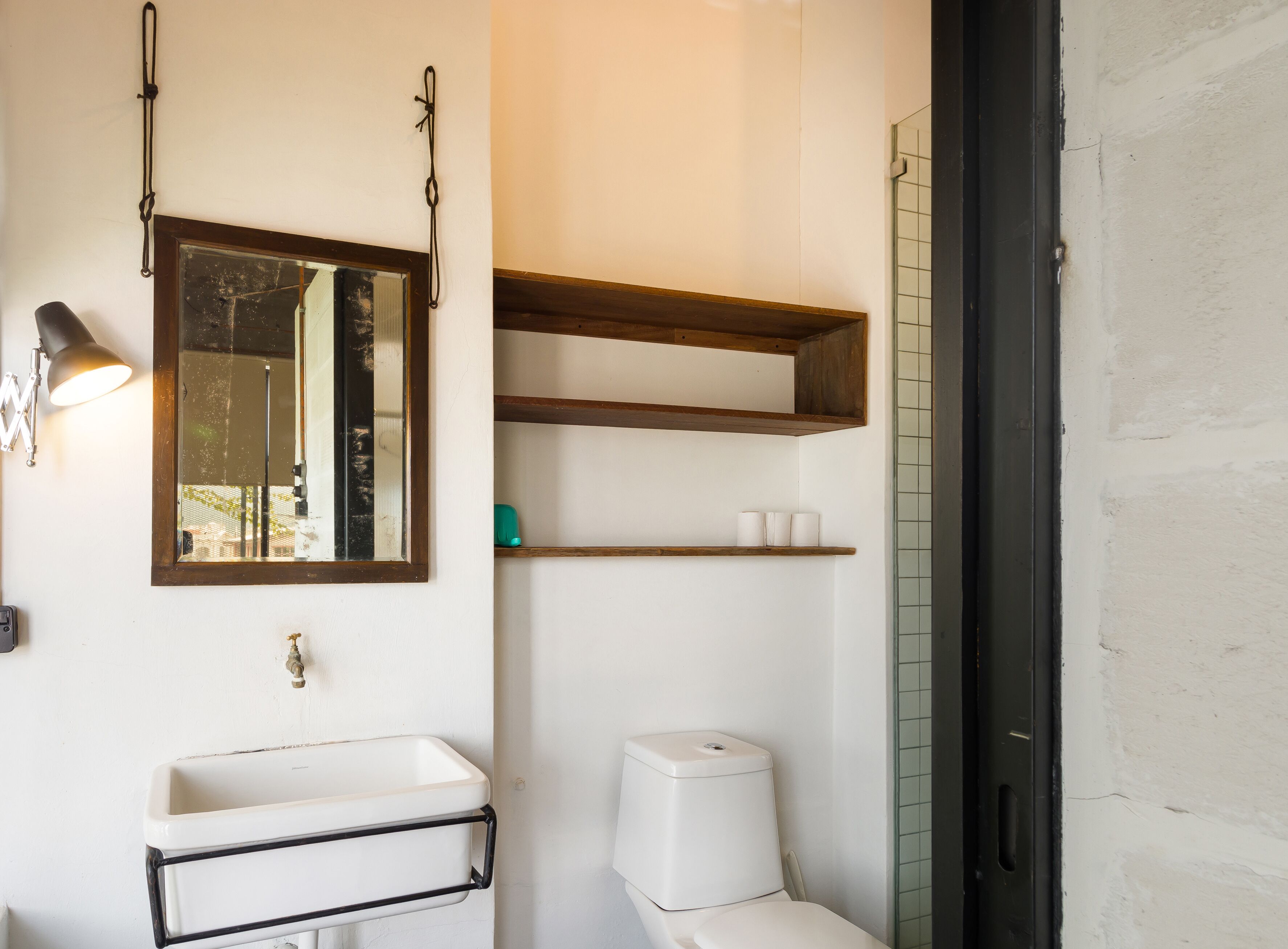 Ein Badezimmer mit weißem Waschbecken, einem Spiegel, einer Toilette und einem Ablagefach mit Pflegeprodukten.