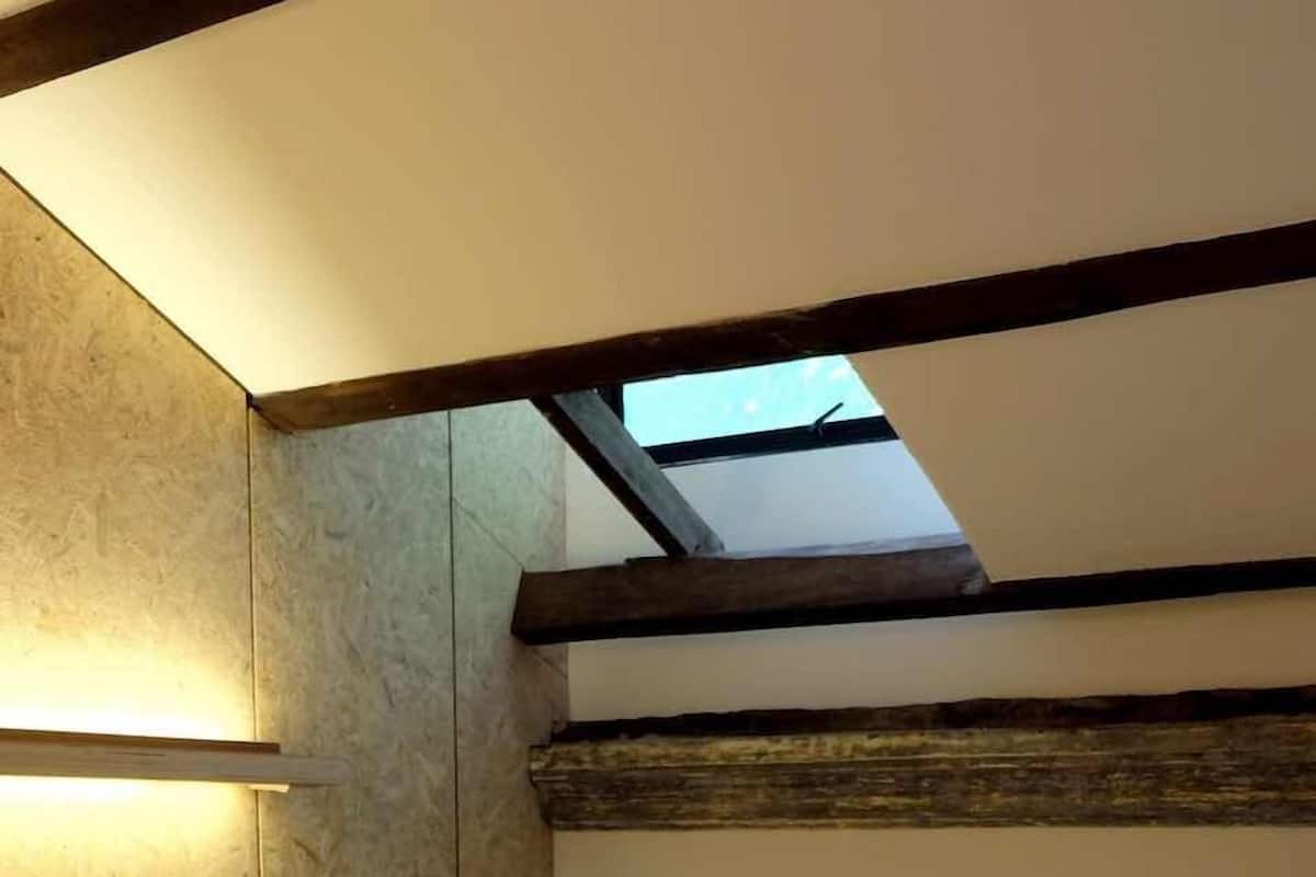 A bedroom with two beds, a skylight, and a television.