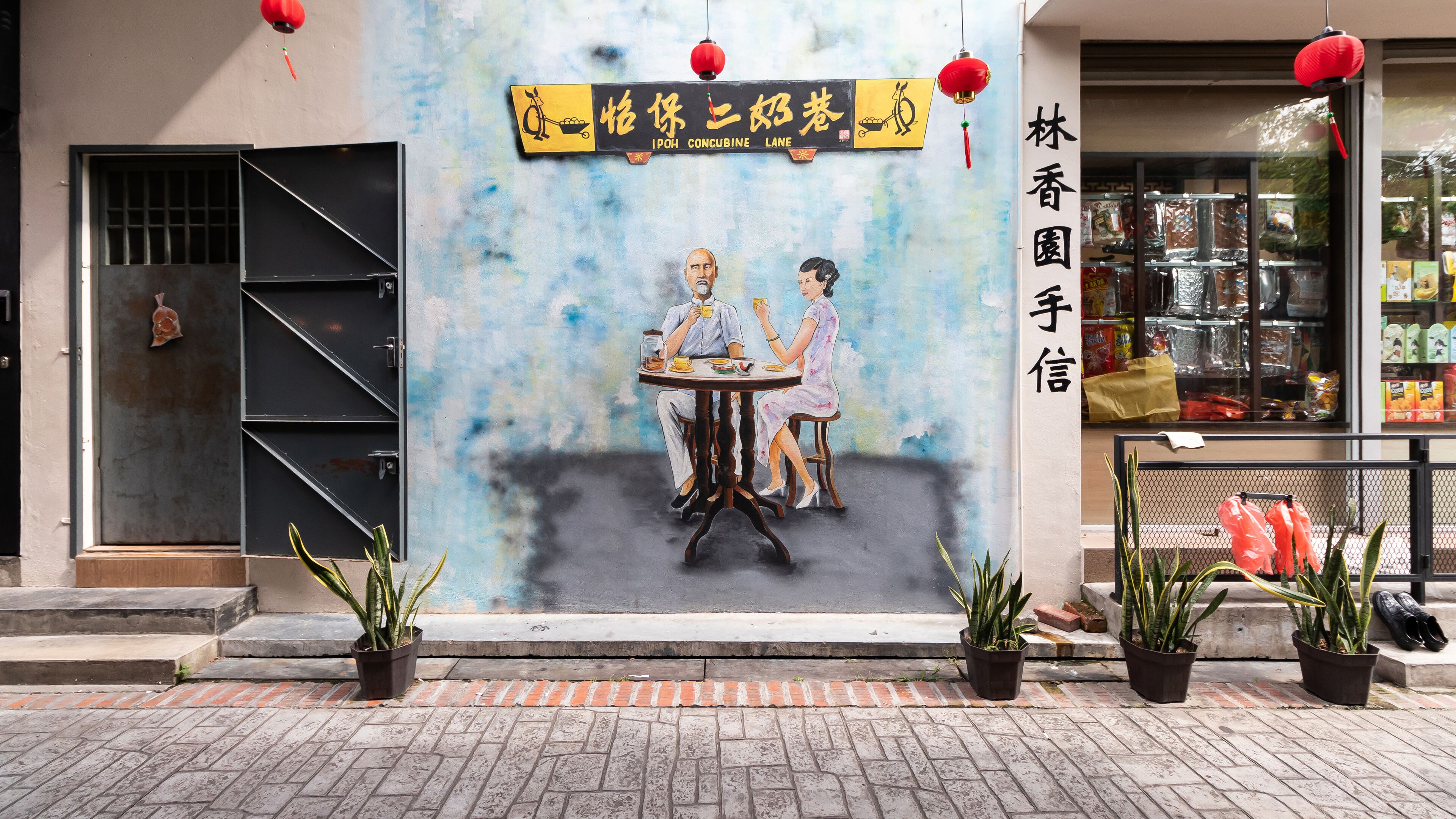 A storefront with a mural of two people dining, a sign reading "IPOH CONCUBINE LANE," and a shop window displaying various products.