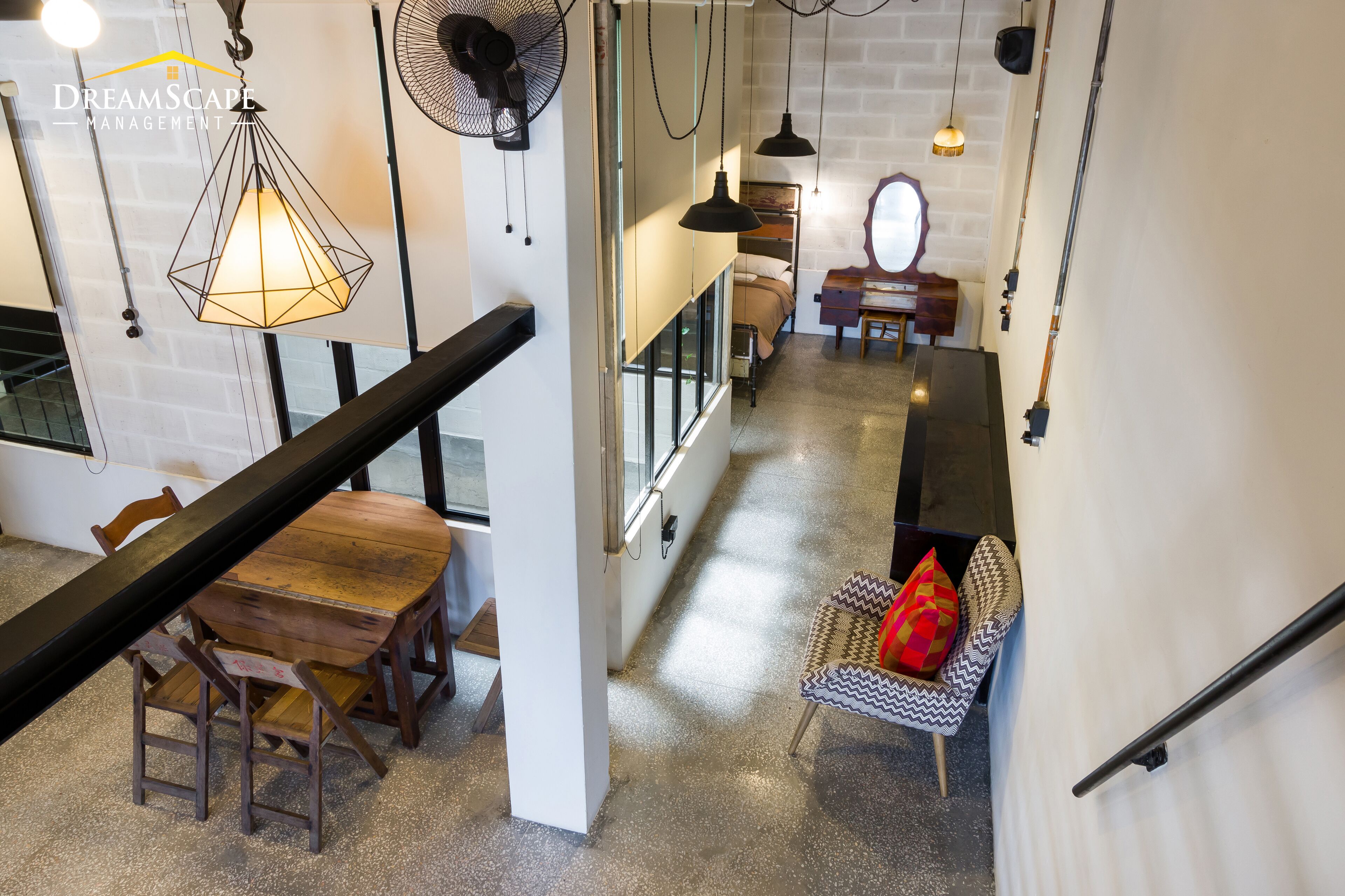 Un interior moderno con una mesa de comedor de madera, sillas, una lámpara colgante y una escalera que sube a un nivel superior.