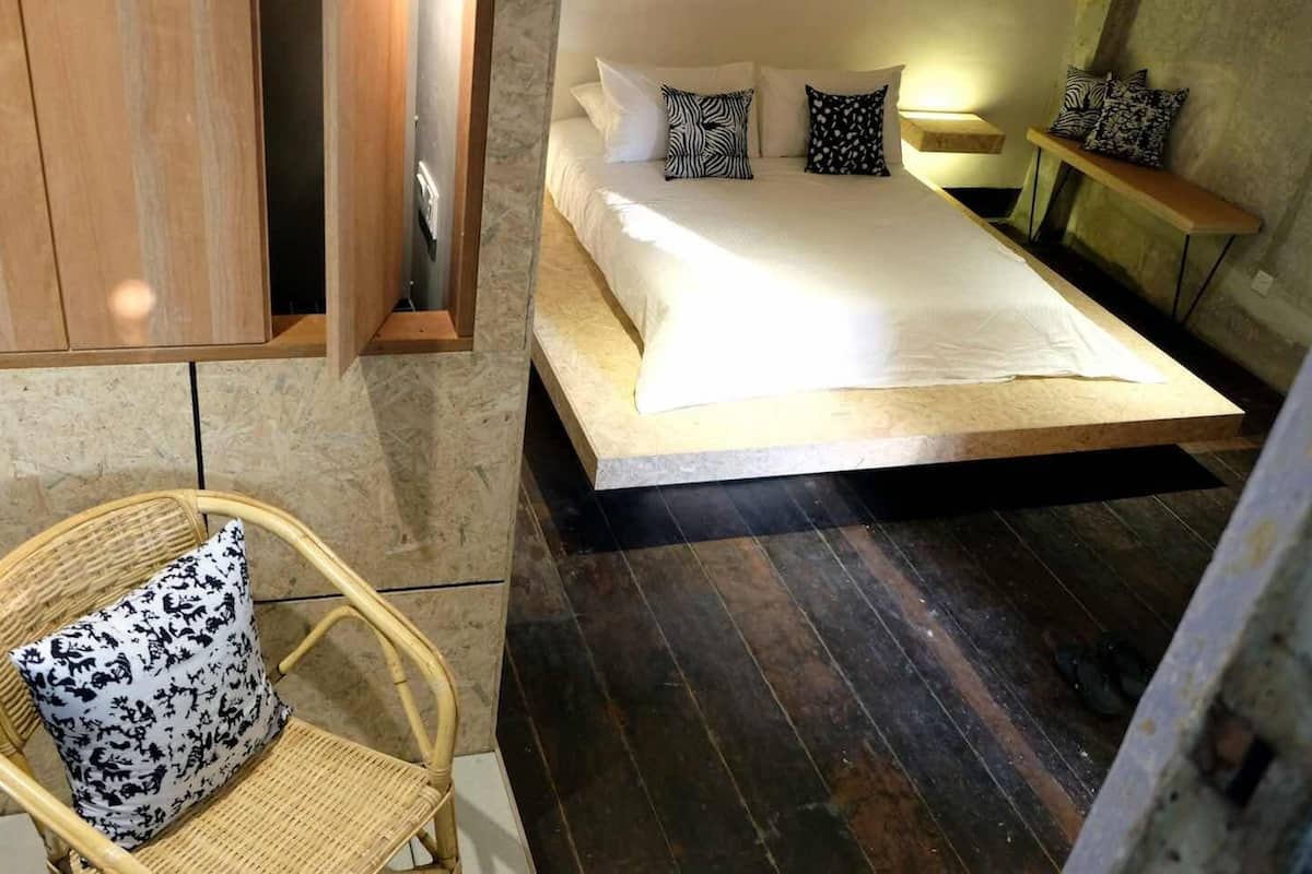 A bedroom with a bed, a chair, and a wooden cabinet.