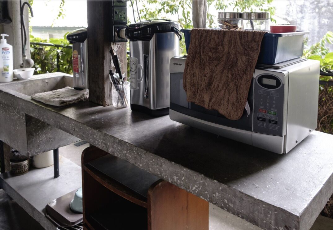 A kitchen with a microwave, a kettle, and a coffee maker on the counter.
