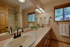 Un baño con un espejo grande, dos lavamanos, una ventana y una lámpara en el techo.