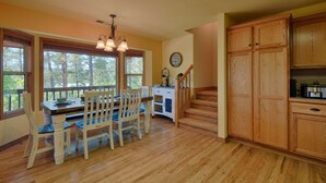 A dining area with a wooden table and chairs, a chandelier, and a view through large windows. - Wraparound Deck, Stunning Mountain Views, Near Downtown Pagosa & Wolf Creek Ski Area (Pagosa Springs)