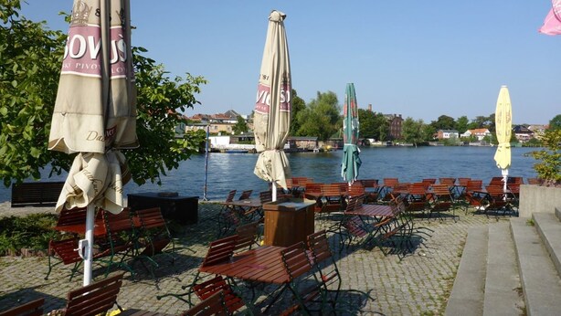 Outdoor seating with umbrellas by a waterfront. - Reihenhaus in Malchow (Malchow)