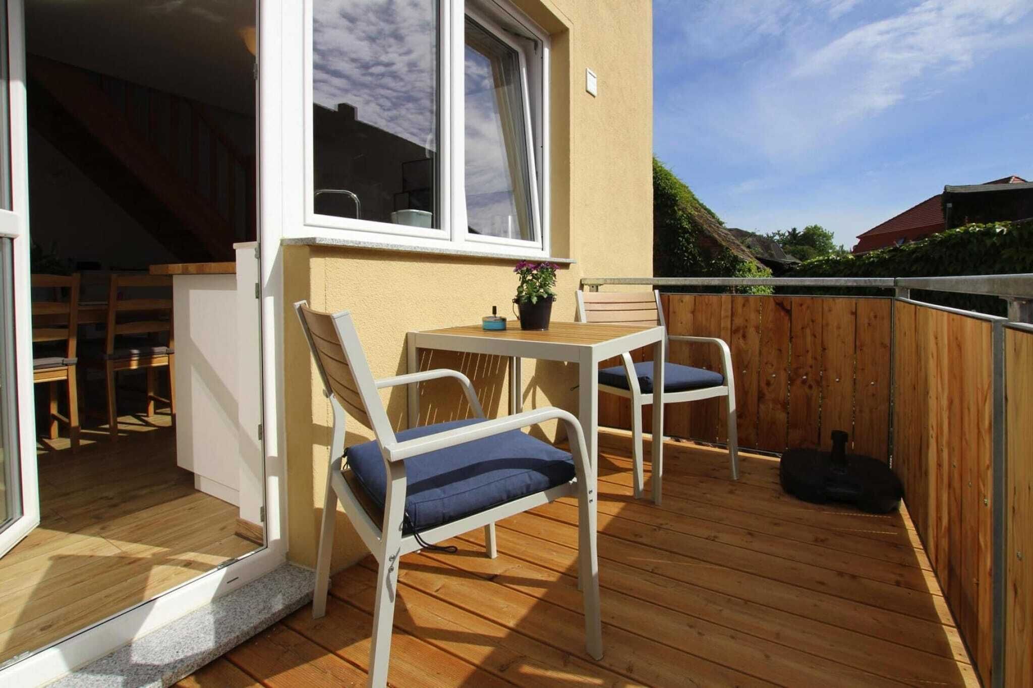 Une terrasse en bois avec une table et des chaises, une fenêtre et une vue sur les environs.