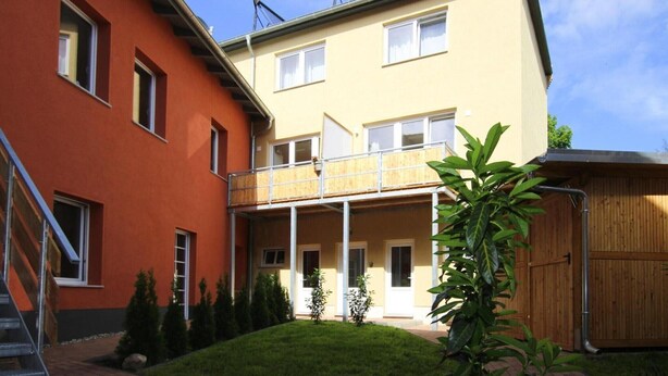 A two-story building with a balcony, a covered outdoor area, and a wooden fence. - Reihenhaus in Malchow (Malchow)