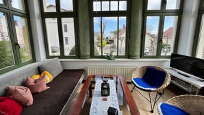 Une pièce avec un canapé, une table sur laquelle se trouve une bouteille, une chaise et un téléviseur.