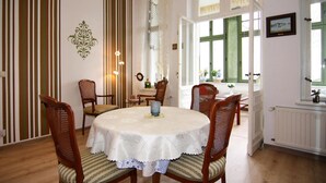 Un coin repas avec une table ronde recouverte d’une nappe blanche, entourée de chaises en bois dotées de coussins à rayures.