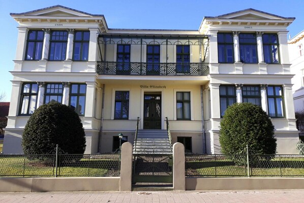 A stately building with a symmetrical facade, large windows, and a central entrance with steps.