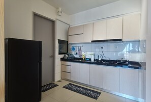 A modern kitchen with light-colored cabinets, a black refrigerator, and a black countertop.