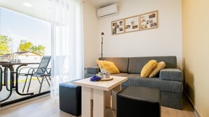 A modern living room with a grey sofa, a small table with a vase, and black ottomans. - Apartments Banonia - Morning Dawn (Verzej)
