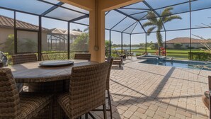 A covered patio with a pool, wicker furniture, and a view of a golf course. - ⚓Lakeside home with private pool located in Golf & CC!⚓⛳ (Bradenton)