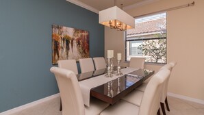 A dining area with a rectangular table, white upholstered chairs, a chandelier, and a painting on the wall. - ⚓Lakeside home with private pool located in Golf & CC!⚓⛳ (Bradenton)