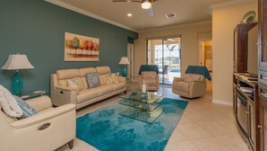 A living room with a beige sofa, a glass coffee table, and a ceiling fan. - ⚓Lakeside home with private pool located in Golf & CC!⚓⛳ (Bradenton)