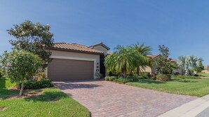 A residential driveway leading to a garage, surrounded by well-maintained lawns and palm trees. - ⚓Lakeside home with private pool located in Golf & CC!⚓⛳ (Bradenton)