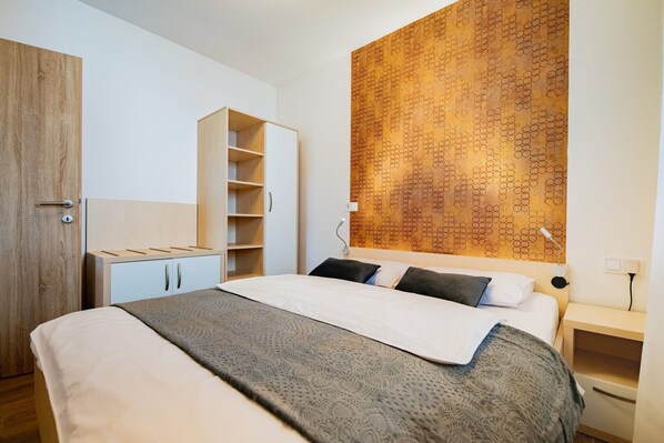 Un dormitorio moderno con una cama, un armario, una estantería empotrada y una pared con estampado.