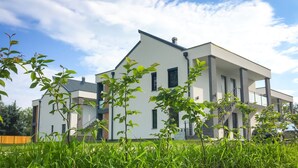 Ein modernes, zweistöckiges Haus mit Flachdach, großen Fenstern und einer sichtbaren Treppe, die zu der oberen Etage führt.