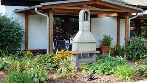 A garden with a stone structure, wooden pergola, and various plants. - Zur Alten Boddenfischerei (Saal)