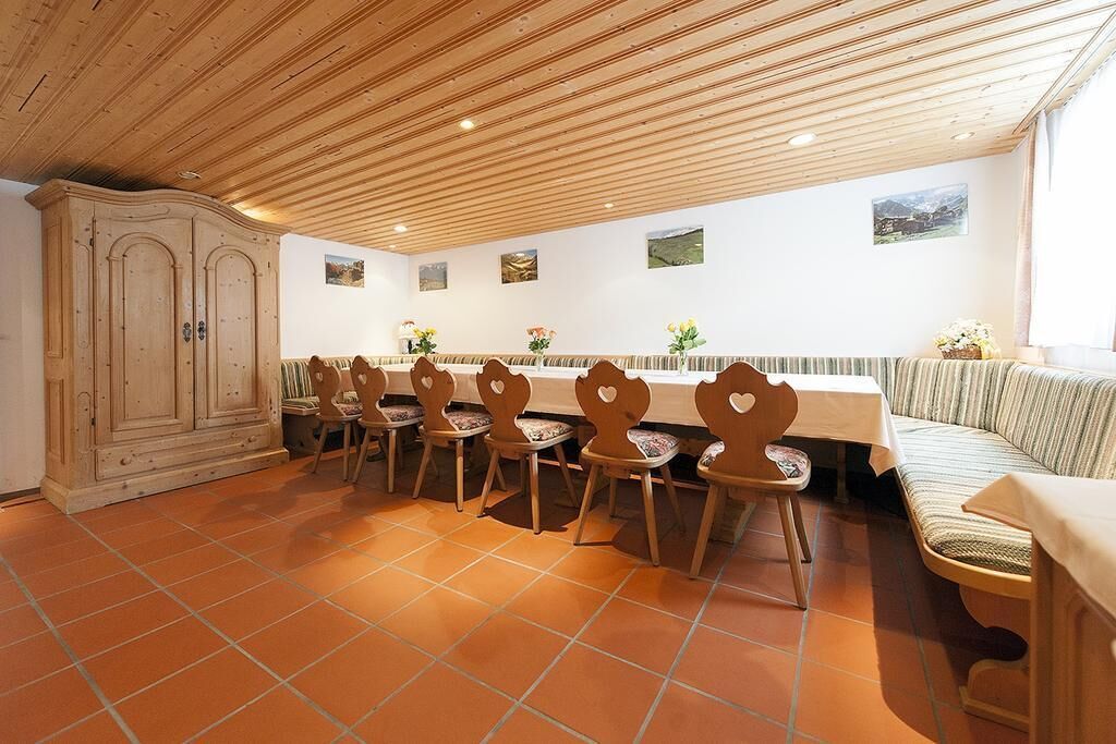 A dining area with a long table, several chairs, a bench, and a cabinet.