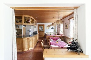 Una cocina acogedora con armarios de madera, una zona de comedor con banco y una estantería para vinos.