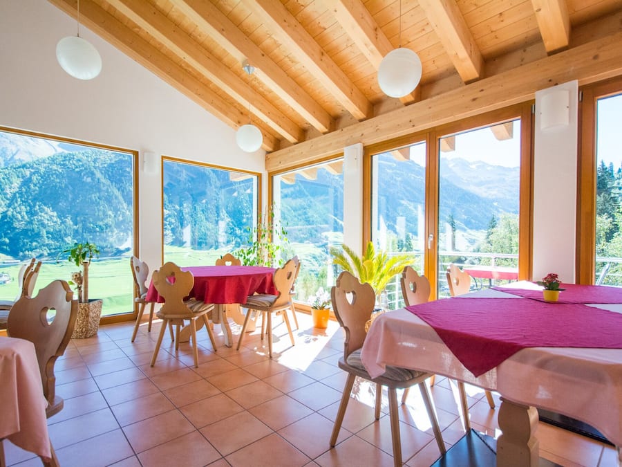 Comedor con vigas de madera, ventanas amplias y vistas a las montañas.