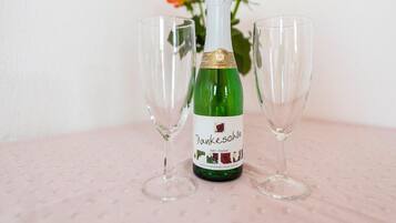 Une bouteille de vin, deux verres vides et un bouquet de roses en arrière-plan.