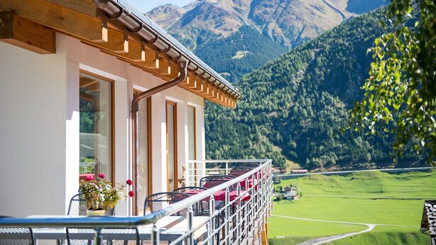 A hotel with a balcony overlooking a mountain and a green valley. - Hotel Cuntera (Medel)
