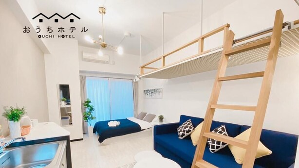 Ein modernes Hotelzimmer mit Etagenbett, einer Couch, einem Essbereich und einer kleinen Küche.