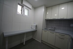 Une cuisine de taille réduite avec des meubles blancs, un plan de travail gris, une fenêtre et un évier.