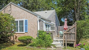 A wooden house with a front porch, a small garden, and a wooden fence.