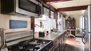 A kitchen with a stove, microwave, and cabinets. There's a sign with a quote on the wall.
