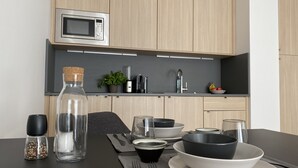 A modern kitchen with wooden cabinets, a built-in microwave, a coffee maker, and a sink. - FRITZTOWER - Apartment (Mitte)