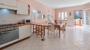 Une cuisine équipée d’une cuisinière à gaz, d’un four, d’un four à micro-ondes et d’un coin repas avec une table et des chaises.