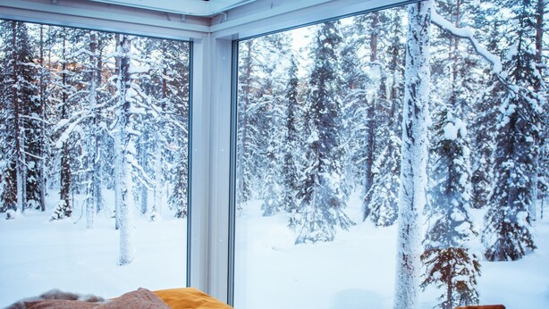 A bedroom with a large window overlooking a snowy forest. - Arctic Skylight Lodge (Muonio)
