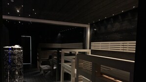 A dimly lit room with bunk beds, a small seating area, and a large window. - Arctic Skylight Lodge (Muonio)